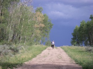 Ashley chugging up a classic Great Divide road with a thunderstorm