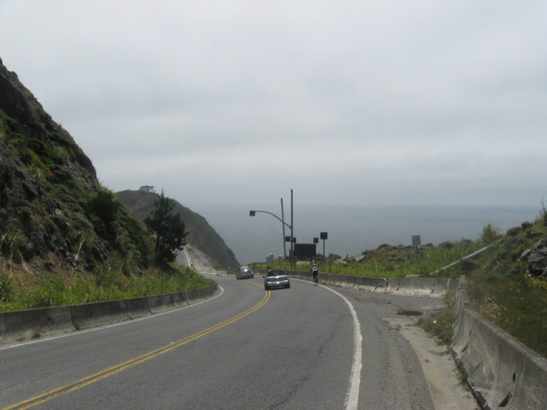 A rider descends Highway 1, toward Devil's Slide, with the Pacific Ocean in the background. The cars are gone now, having been rerouted. Photo by Wayne Cottrell