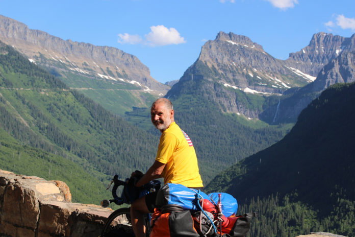 Lou at the location that inspired the Monte Dolack painting, Going to the Sun Highway, Glacier National Park.