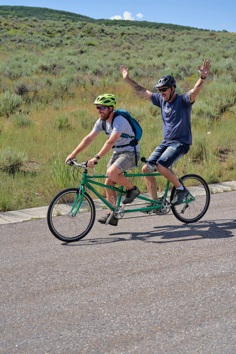 Two National Ability Center riders cycling on tandem bike during summer 2019 cycling session. Photo by Berin Klawiter