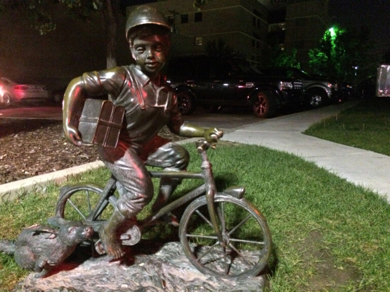 Photo: A Bronze Sculpture of a Child on a Bicycle and Their Dog